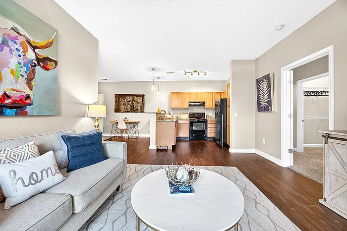 Modern open-concept living area featuring a stylish kitchen, cozy seating with artistic decor, and inviting warm tones.