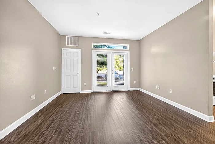 Bright, spacious living room featuring elegant wood flooring and large windows with garden views, perfect for modern living.