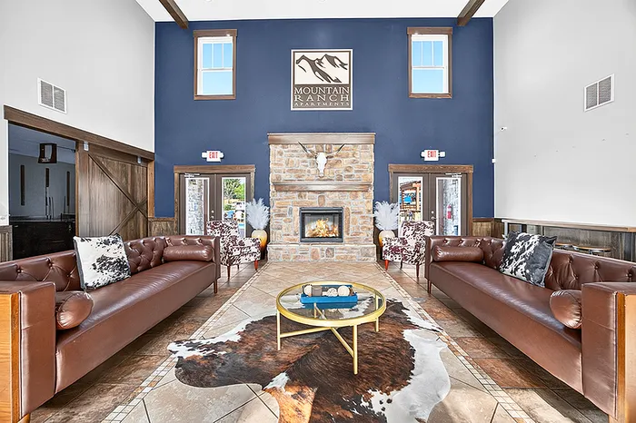 Elegant apartment lounge with cozy fireplace, luxurious leather sofas, and stylish decor at Mountain Ranch Apartments.
