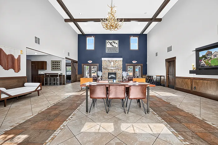 Inviting community space with high ceilings, elegant wooden beams, and a cozy stone fireplace, perfect for relaxation and social gatherings.