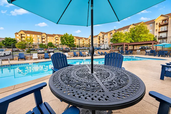 Luxury apartment complex boasting a pristine swimming pool, surrounded by stylish seating and vibrant landscaping, perfect for relaxation and entertainment.