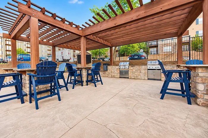 Inviting outdoor patio with pergola, stylish blue seating, and modern BBQ grills perfect for entertaining.