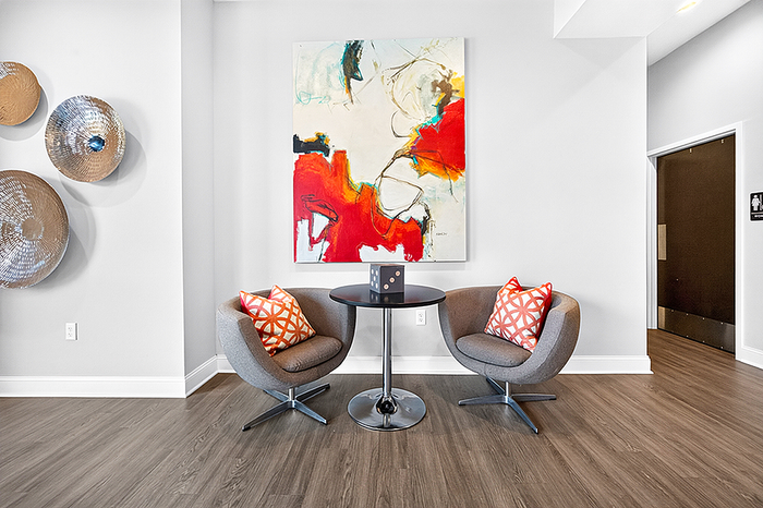 Chic modern lounge area featuring stylish chairs, vibrant abstract artwork, and elegant wood flooring, perfect for relaxation.