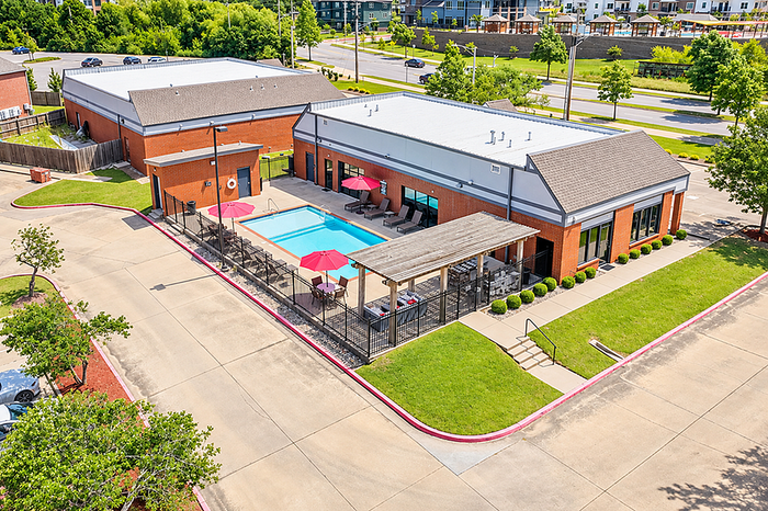 Inviting community space featuring a pristine swimming pool with lounging areas, vibrant red umbrellas, and a barbecue pergola for outdoor relaxation.