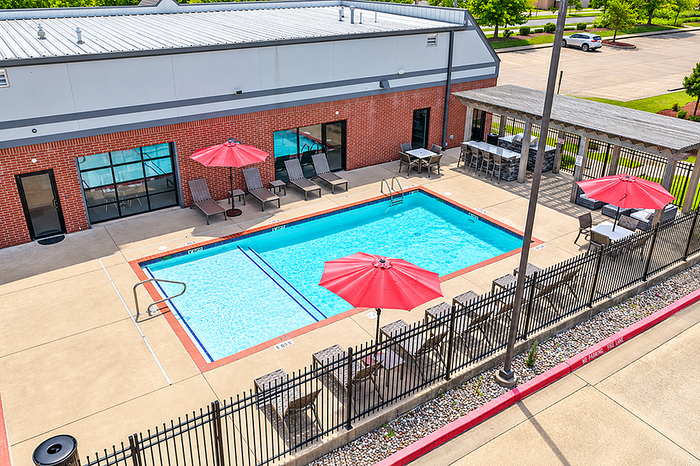 Inviting outdoor pool area with red umbrellas and lounge chairs, perfect for relaxation and social gatherings.