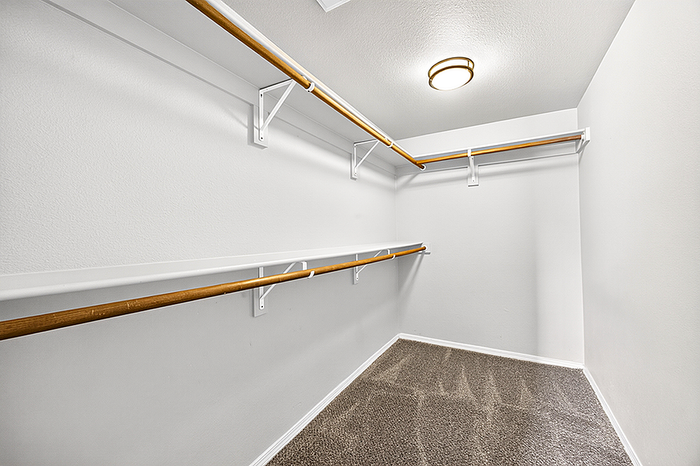 Spacious and well-lit walk-in closet with ample shelving and hanging space, perfect for organized living.