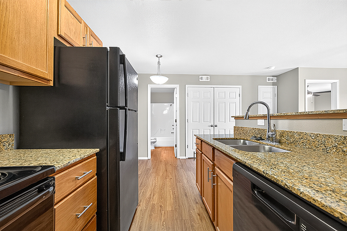 Modern kitchen with sleek granite countertops, rich wooden cabinetry, and stainless steel sink, offering a blend of style and functionality.