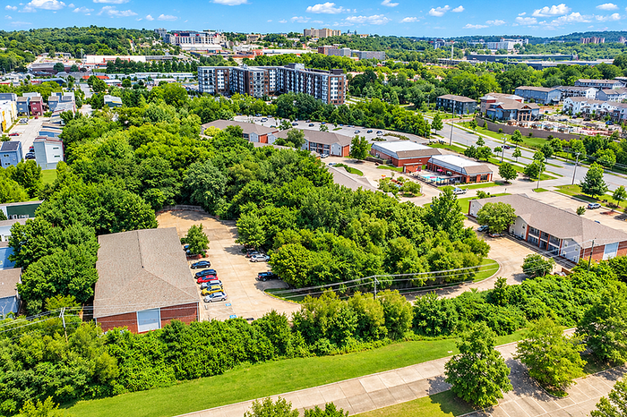 Vibrant aerial view of a green neighborhood showcasing lush trees, modern buildings, and a well-planned residential area.
