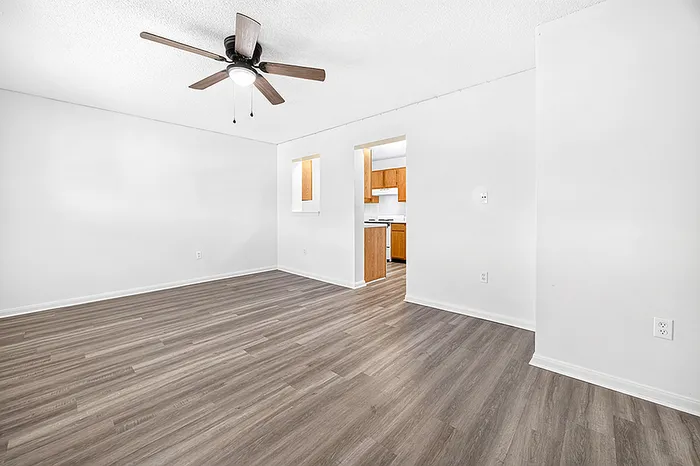 Modern apartment interior showcasing elegant wood flooring, open living area, and a cozy kitchen with warm wooden cabinetry.