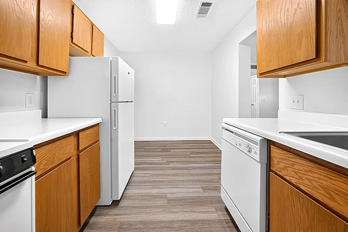 Modern kitchen with sleek white appliances, wood cabinets, and elegant flooring.