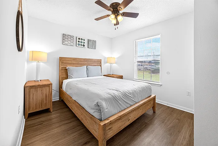 Bright and inviting bedroom with a natural wood bed frame, stylish decor, and ample natural light.