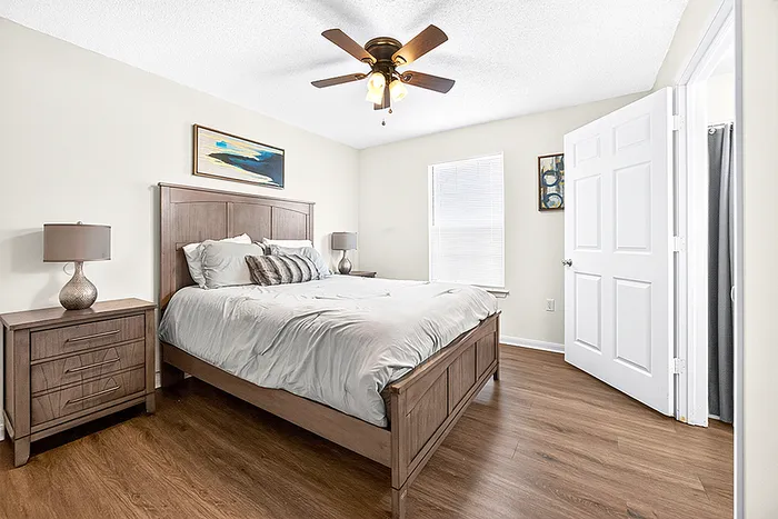 Inviting bedroom with elegant wooden furniture, plush bedding, and modern ceiling fan, perfect for relaxation.