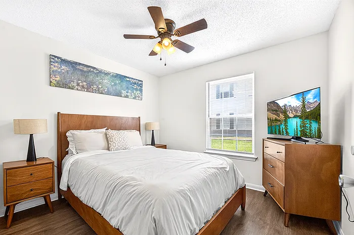Inviting bedroom with elegant wooden furniture, warm lighting, and a large window providing ample natural light.