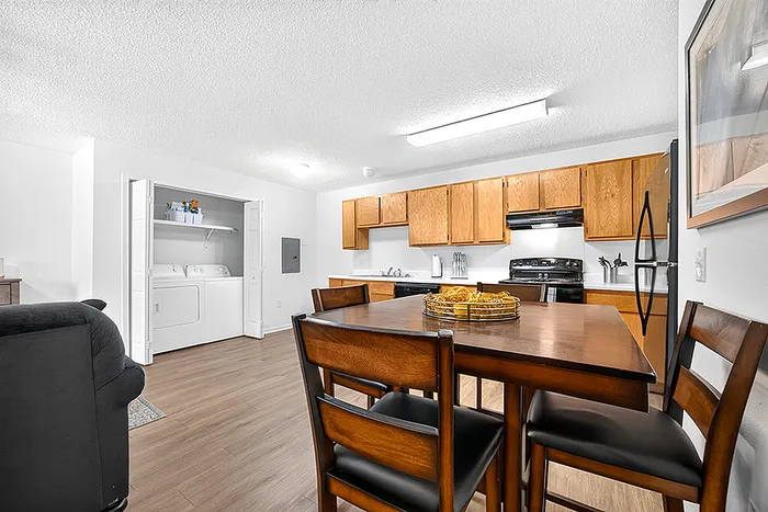 Inviting kitchen and dining area with warm wooden cabinetry, modern appliances, and a convenient in-unit laundry niche.