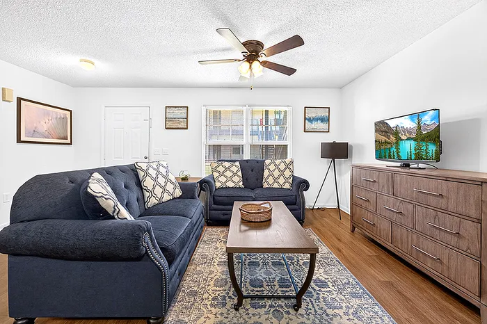 Charming living room with elegant navy sofas, stylish wooden coffee table, and chic decor, perfect for relaxation and entertainment.