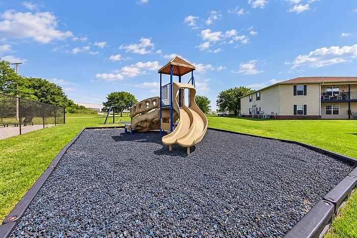 Inviting playground with slides and swing set in a sunny, green apartment community.