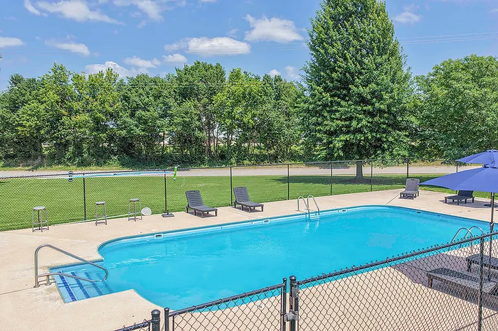 Inviting outdoor pool area with sun loungers and vibrant greenery, perfect for relaxation and leisure.