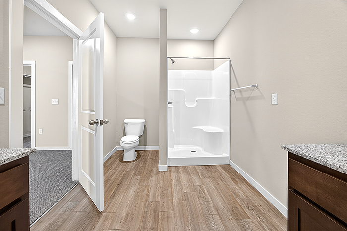 Modern bathroom featuring hardwood floors, a sleek shower, and elegant fixtures with neutral tones.