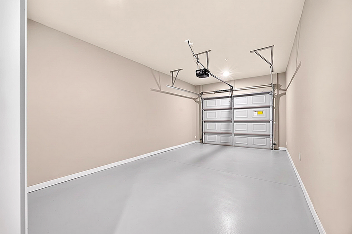 Spacious modern garage with sleek gray flooring and automatic door opener, ideal for secure parking or extra storage.