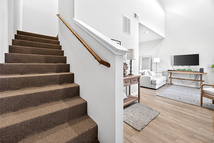 Modern interior featuring elegant staircase leading to a bright living room with stylish decor and cozy seating area.