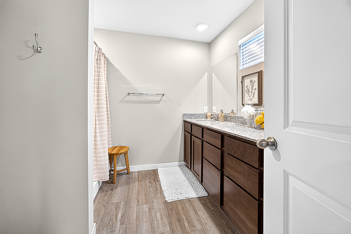 Elegant bathroom featuring a spacious granite countertop, double sink vanity, and stylish wood cabinetry with modern accents.