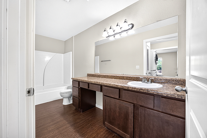 Spacious modern bathroom with elegant granite countertop, ample storage, and bright lighting.
