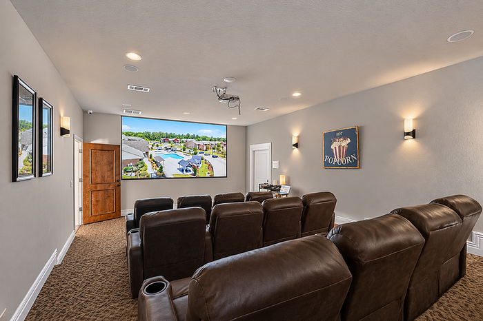 Luxurious home theater room with plush leather seating, stylish decor, and a large projector screen showcasing vibrant outdoor imagery.