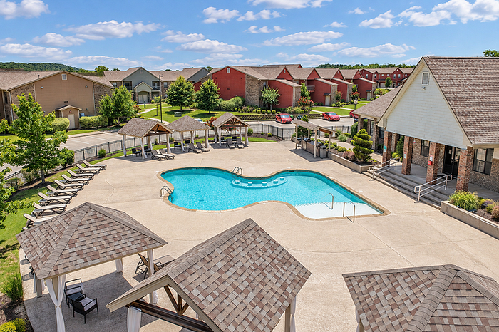 Inviting apartment complex with a sparkling outdoor pool, cozy cabanas, and beautifully landscaped surroundings on a sunny day.