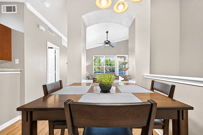 Bright dining area with elegant furniture, stylish lighting, and a lush green view through large windows.
