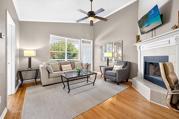 Inviting living room with elegant decor, cozy armchairs, and a modern fireplace, enhanced by natural light through large windows.