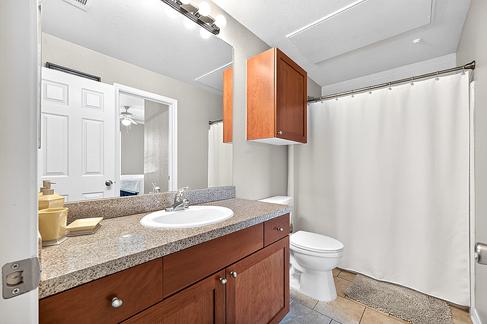 Inviting bathroom featuring a sleek granite countertop, rich wooden cabinetry, and a polished chrome faucet, all bathed in bright natural light.