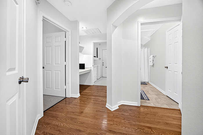 Inviting hallway in modern apartment featuring elegant hardwood floors, white doors, and a convenient built-in desk space.