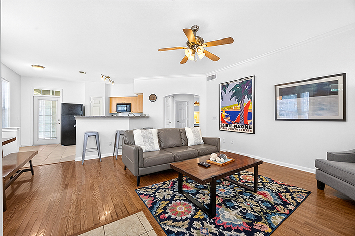 Bright and inviting living room with cozy sofa, colorful rug, and modern kitchen; perfect for relaxation and entertaining.