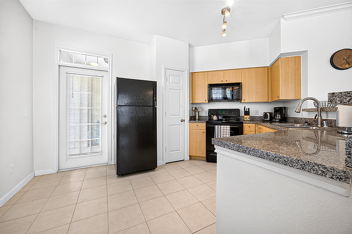 Bright and contemporary kitchen with sleek granite countertops, modern black appliances, and ample natural light.