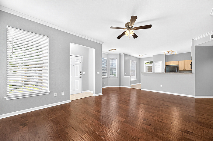 Bright and spacious open-concept living area with elegant hardwood flooring, modern ceiling fan, and abundant natural light.
