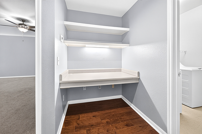 Cozy workspace nook with built-in shelves and elegant lighting, adjacent to a charming carpeted room.