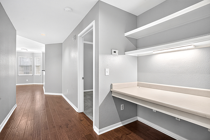 Chic apartment hallway with elegant hardwood floors, built-in desk, ample shelving, and natural lighting.