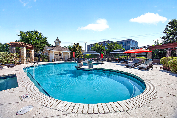 Inviting outdoor pool area with stylish loungers, vibrant umbrellas, and charming pavilion, perfect for relaxation and leisure.