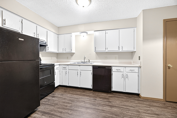 Contemporary kitchen with sleek white cabinetry, modern appliances, and elegant wood flooring.