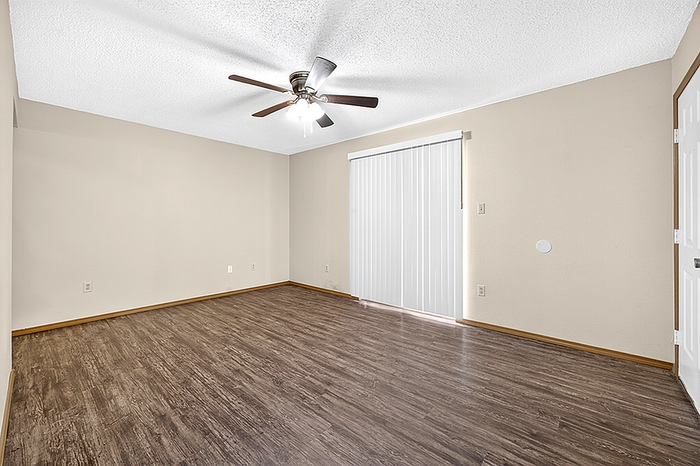 Bright, spacious room with elegant wood flooring and ceiling fan, perfect for a cozy living space.