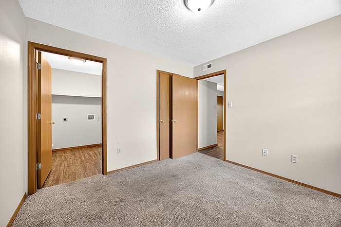 Bright and inviting apartment room featuring plush carpeting, elegant wooden doors, and ample natural lighting.