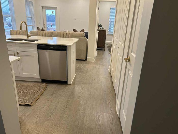 Inviting modern kitchen with sleek appliances and open layout leading to a cozy living area, showcasing stylish wooden flooring.