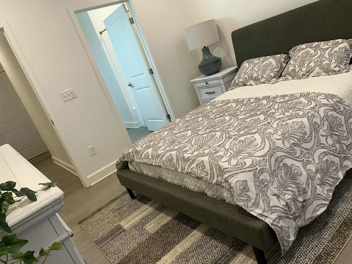 Elegant bedroom featuring a plush bed with patterned bedding, chic white nightstand, and cozy ambience perfect for relaxation.
