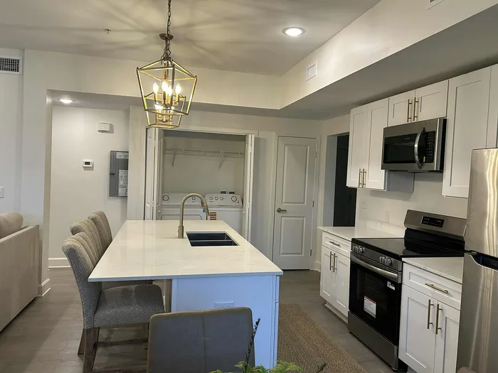 Modern kitchen with sleek stainless steel appliances, elegant white cabinetry, and a chic island with plush seating, exuding sophistication and comfort.