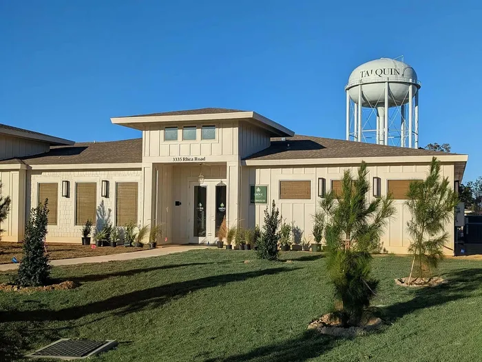 Charming and modern building exterior with well-maintained landscaping, situated under a clear blue sky near a distinctive water tower.