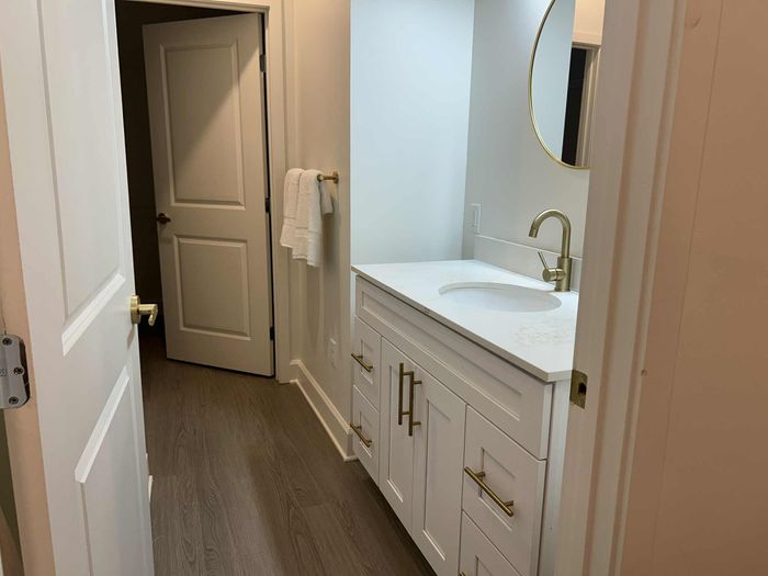 Elegant bathroom with modern white vanity, marble countertop, and gold fixtures, offering a stylish and serene space.