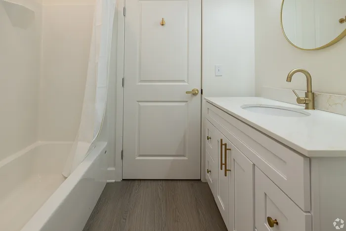 Elegant bathroom featuring modern fixtures, a sleek gold faucet, and a stylish white vanity with ample storage.
