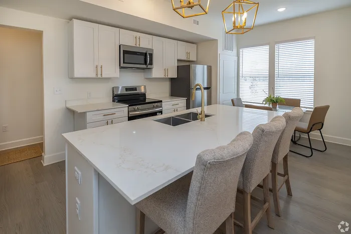 Modern kitchen with sleek marble countertops, stylish pendant lighting, and stainless steel appliances, ideal for culinary enthusiasts.