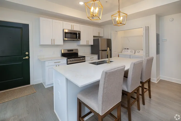 Modern kitchen with sleek marble island, elegant pendant lighting, and stainless steel appliances, perfect for gourmet cooking and entertaining.
