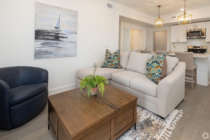 Inviting open-concept living space with elegant decor, cozy sofa, chic armchair, and stylish kitchen area, perfect for relaxation and entertaining.